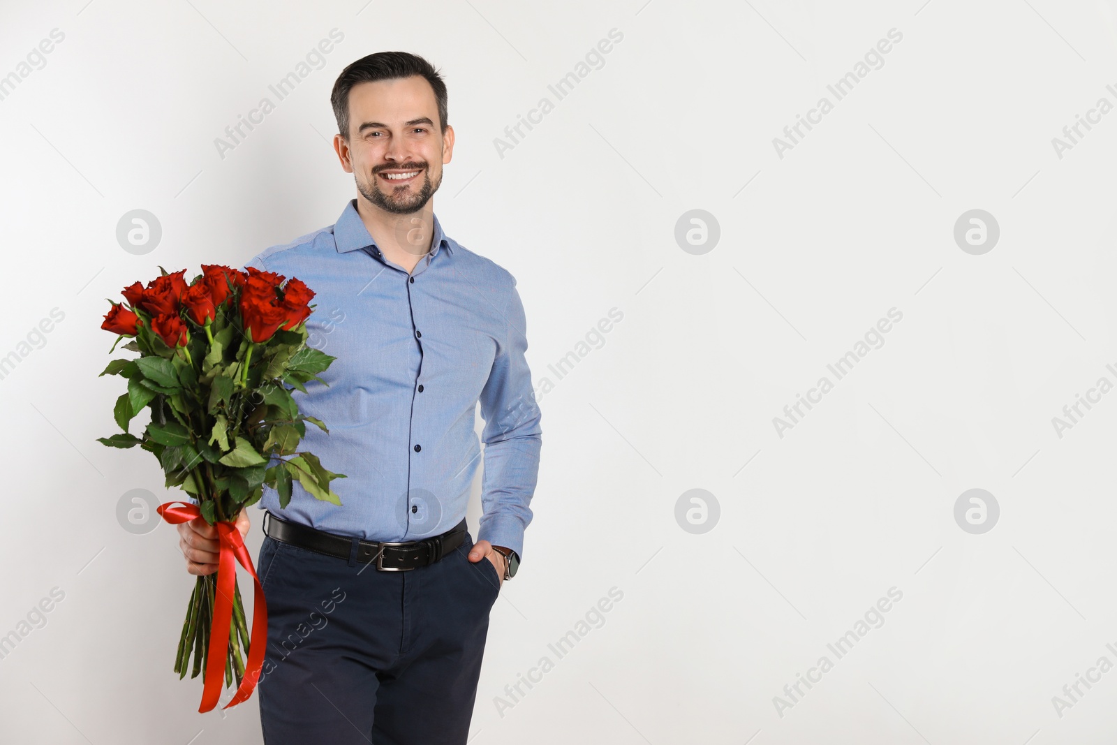 Photo of Happy Valentine's Day. Handsome man with bouquet of roses on white background. Space for text