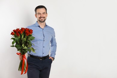 Photo of Happy Valentine's Day. Handsome man with bouquet of roses on white background. Space for text