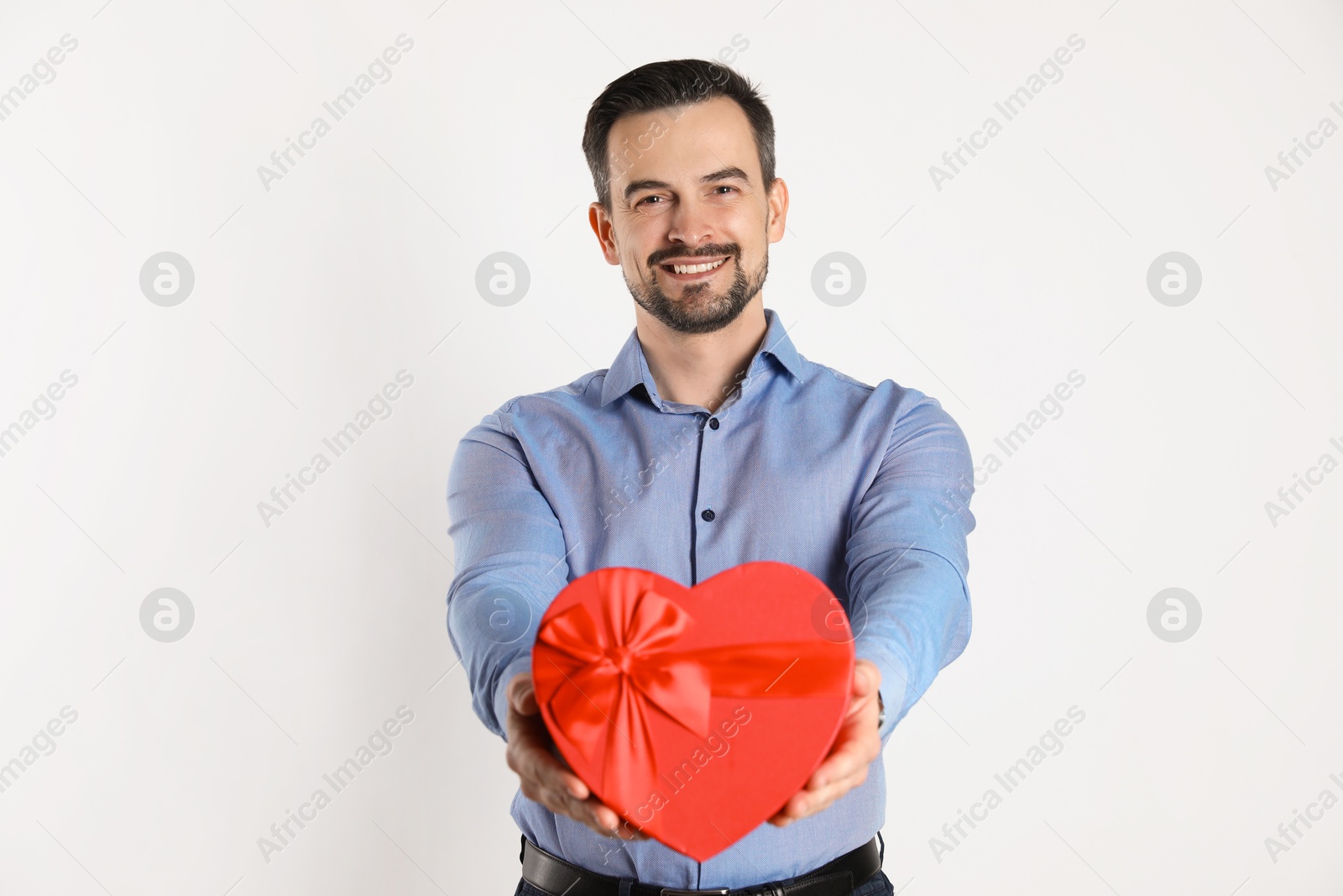 Photo of Happy Valentine's Day. Handsome man with heart shaped gift box on white background