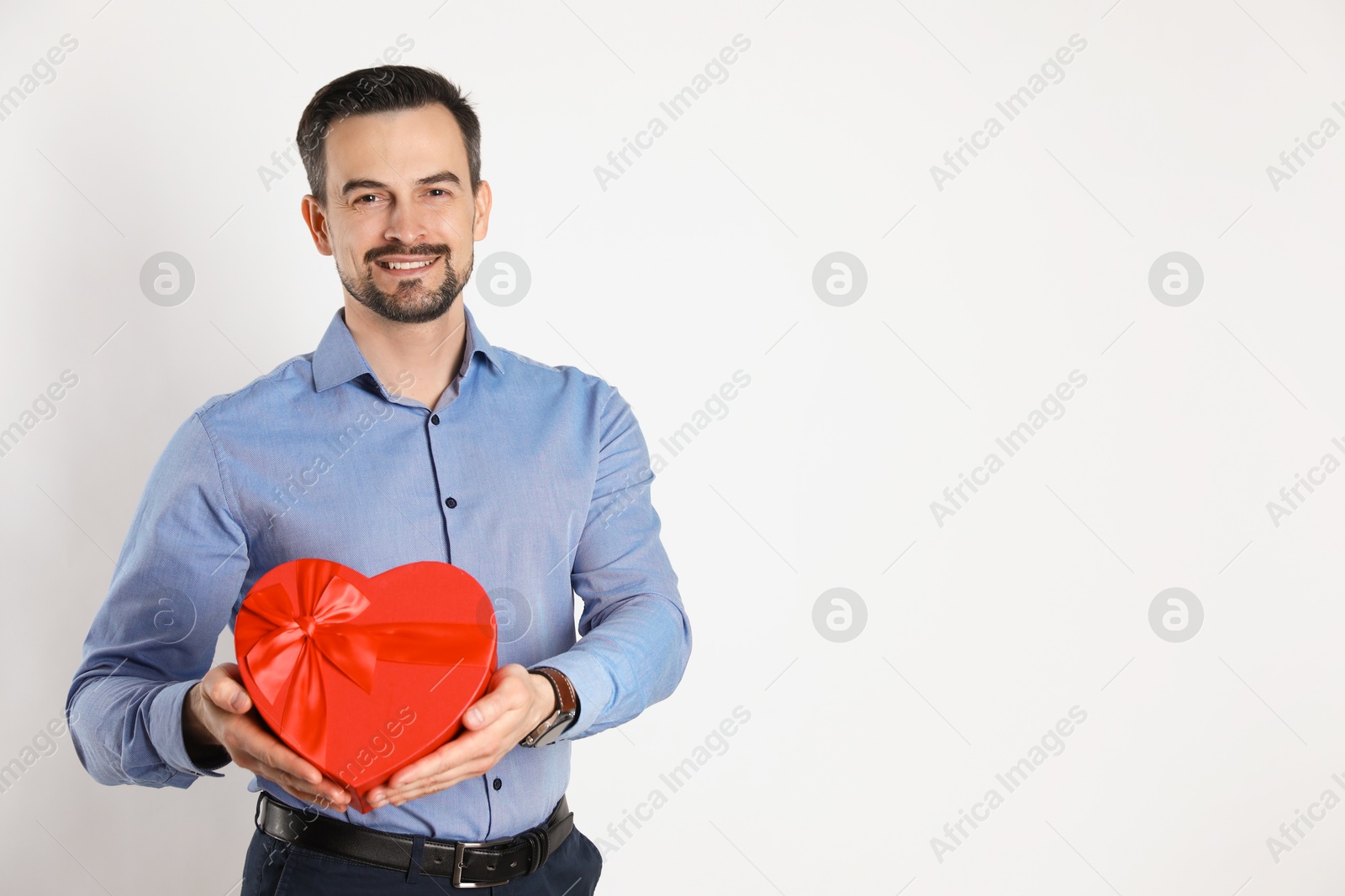 Photo of Happy Valentine's Day. Handsome man with heart shaped gift box on white background. Space for text