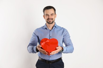 Photo of Happy Valentine's Day. Handsome man with heart shaped gift box on white background