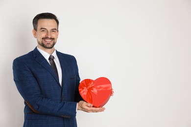 Photo of Happy Valentine's Day. Handsome man with heart shaped gift box on white background. Space for text