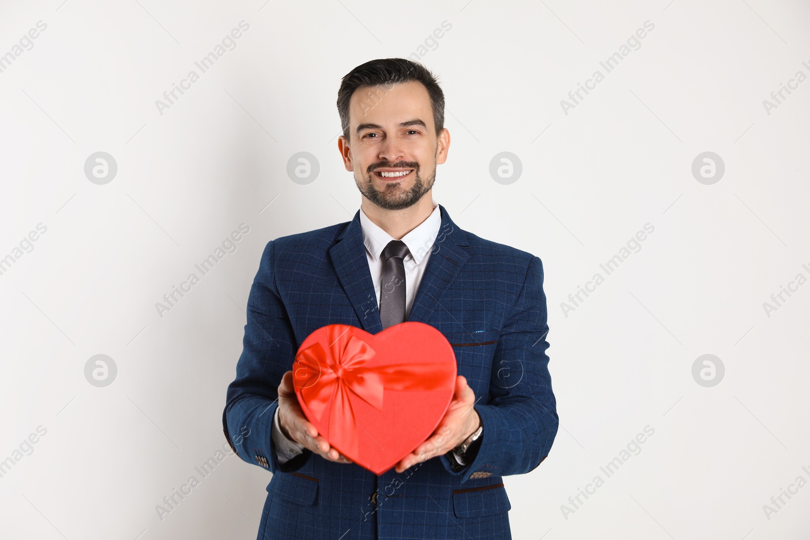 Photo of Happy Valentine's Day. Handsome man with heart shaped gift box on white background