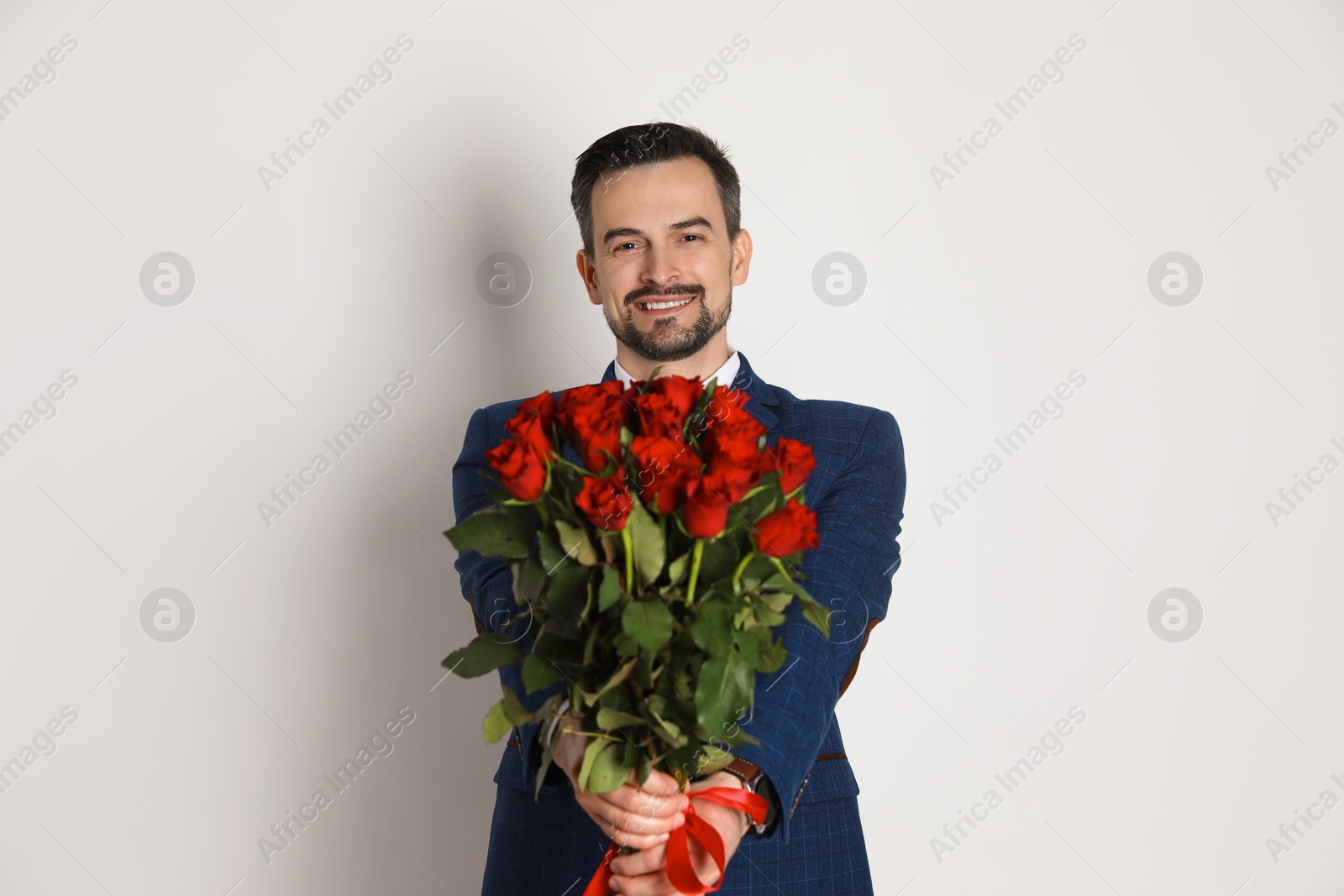 Photo of Happy Valentine's Day. Handsome man with bouquet of roses on white background