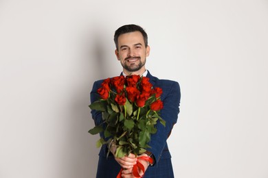 Photo of Happy Valentine's Day. Handsome man with bouquet of roses on white background