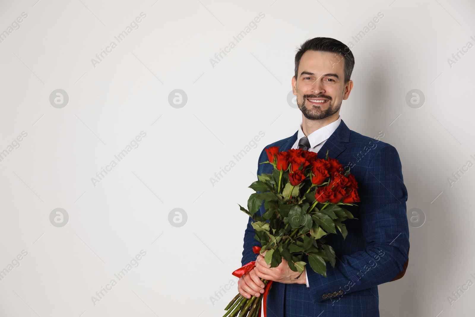 Photo of Happy Valentine's Day. Handsome man with bouquet of roses on white background. Space for text