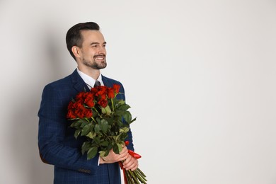 Photo of Happy Valentine's Day. Handsome man with bouquet of roses on white background. Space for text