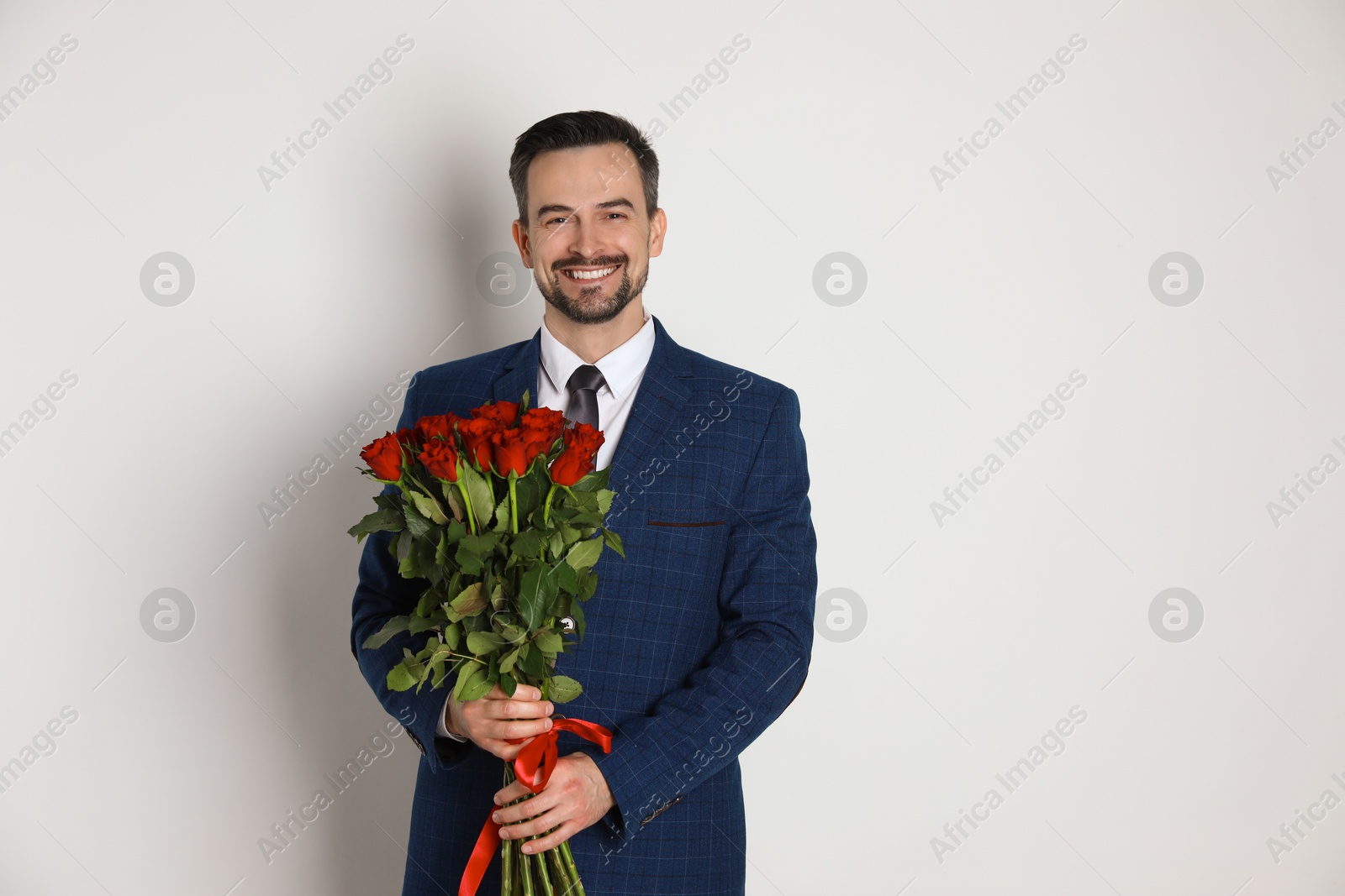 Photo of Happy Valentine's Day. Handsome man with bouquet of roses on white background