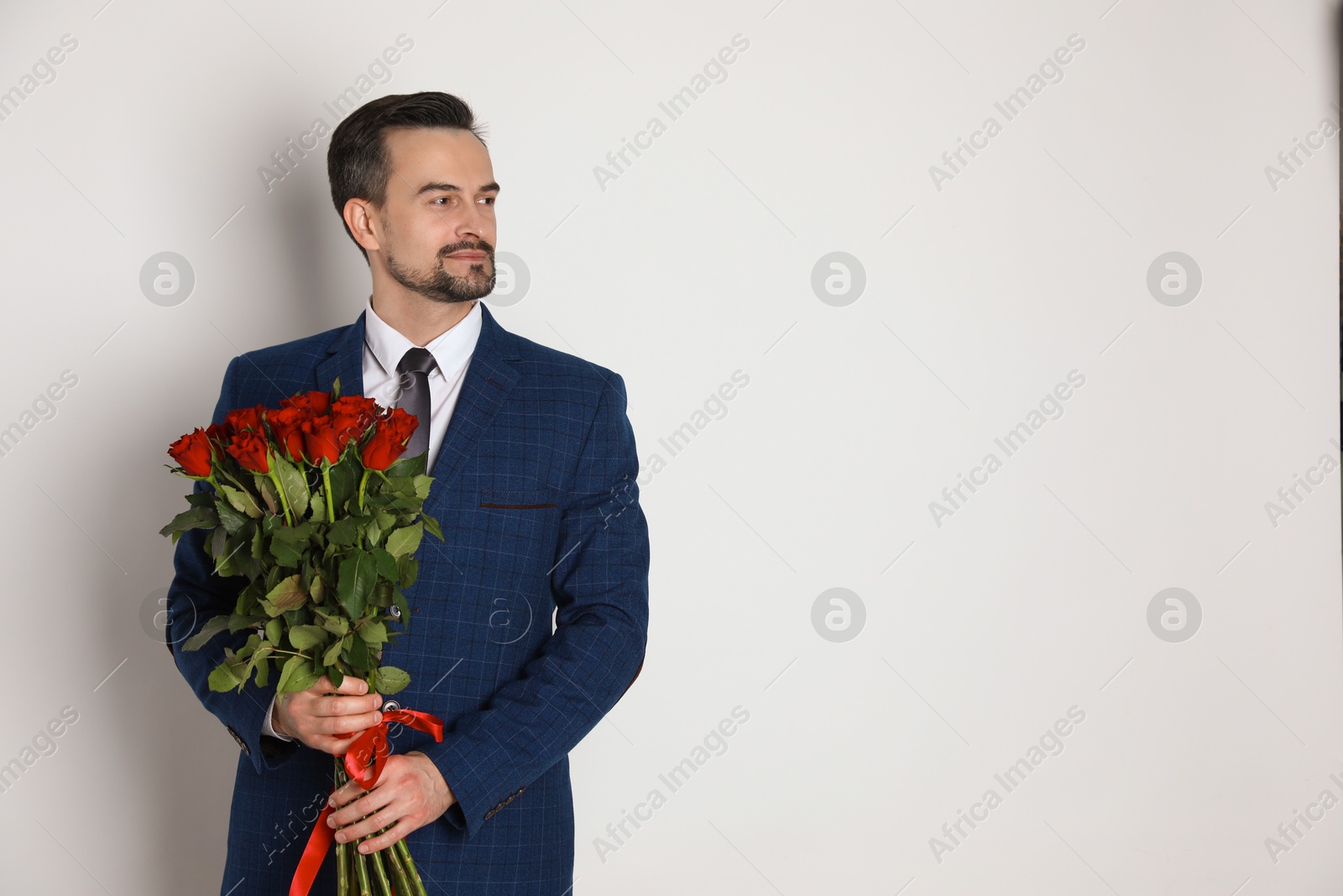 Photo of Happy Valentine's Day. Handsome man with bouquet of roses on white background. Space for text