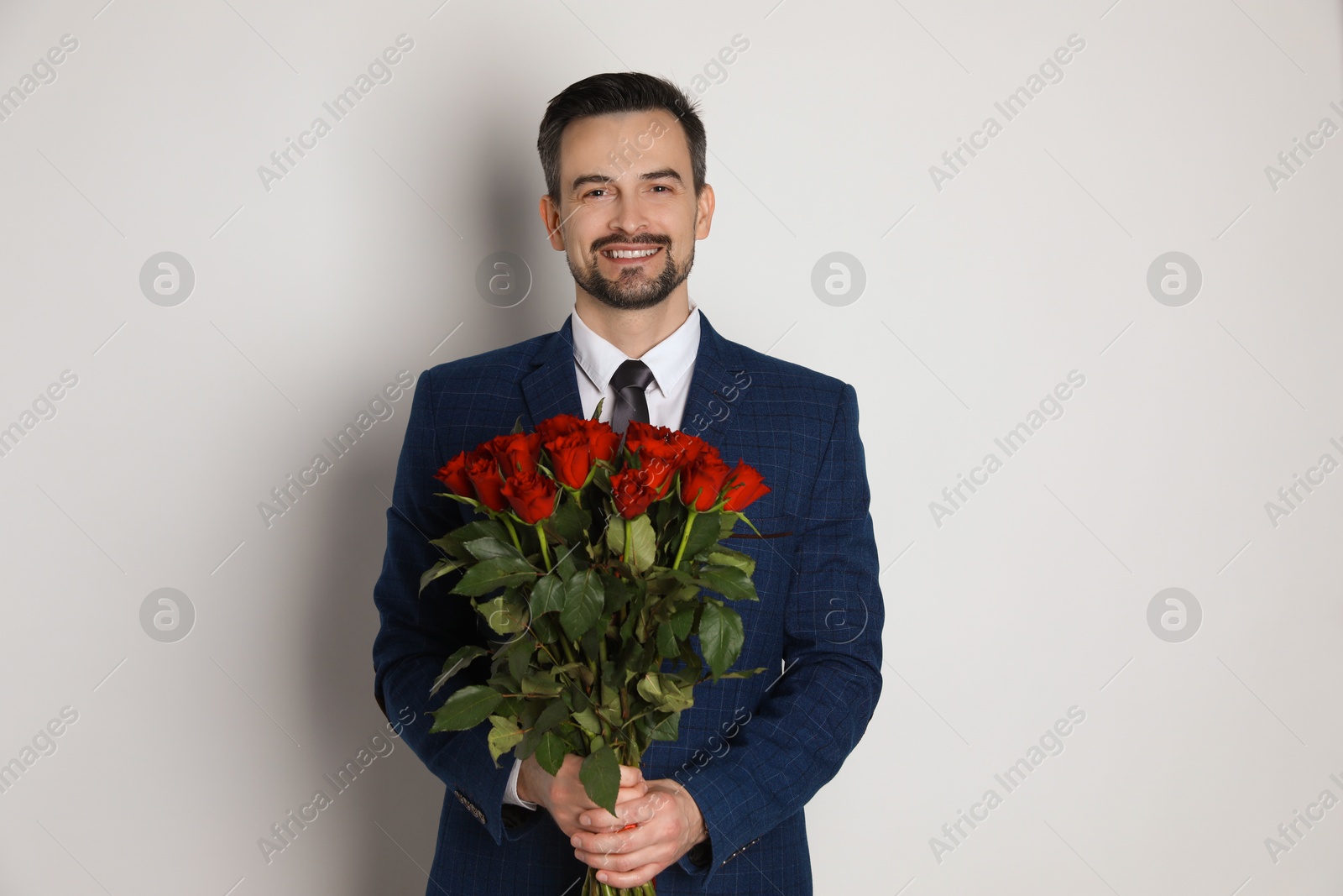 Photo of Happy Valentine's Day. Handsome man with bouquet of roses on white background