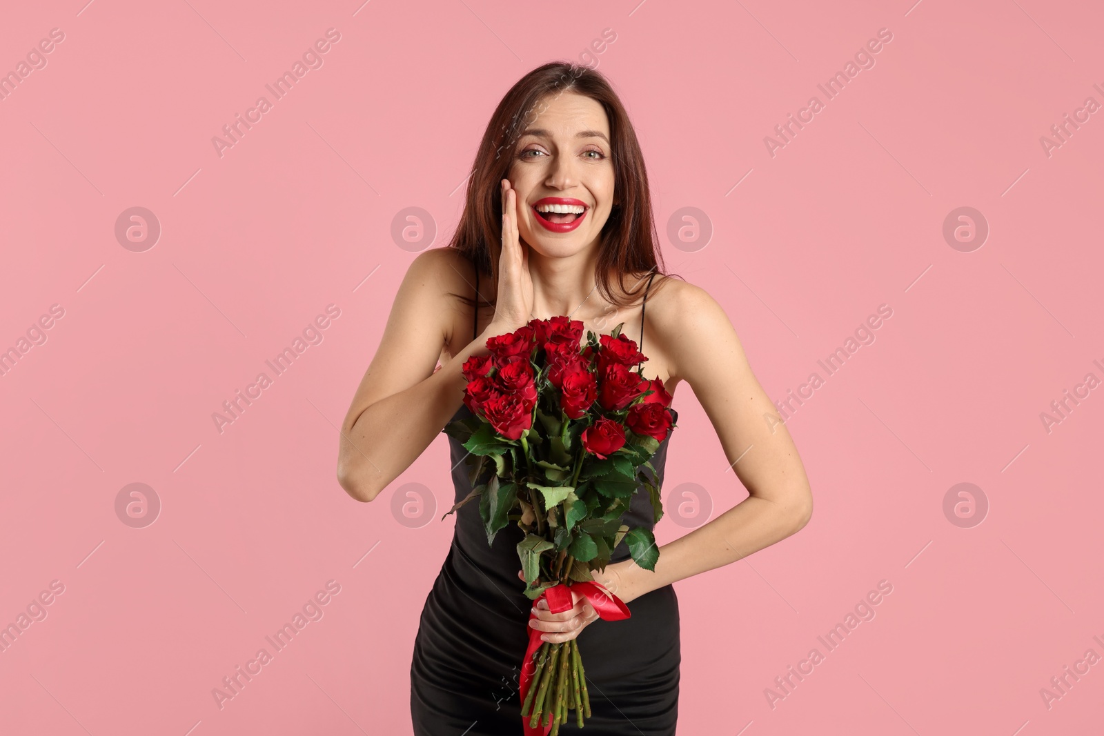 Photo of Happy Valentine's Day. Surprised woman with bouquet of roses on pink background