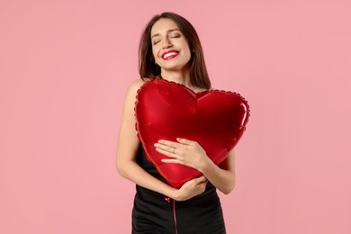 Photo of Happy Valentine's Day. Beautiful woman with heart shaped balloon on pink background