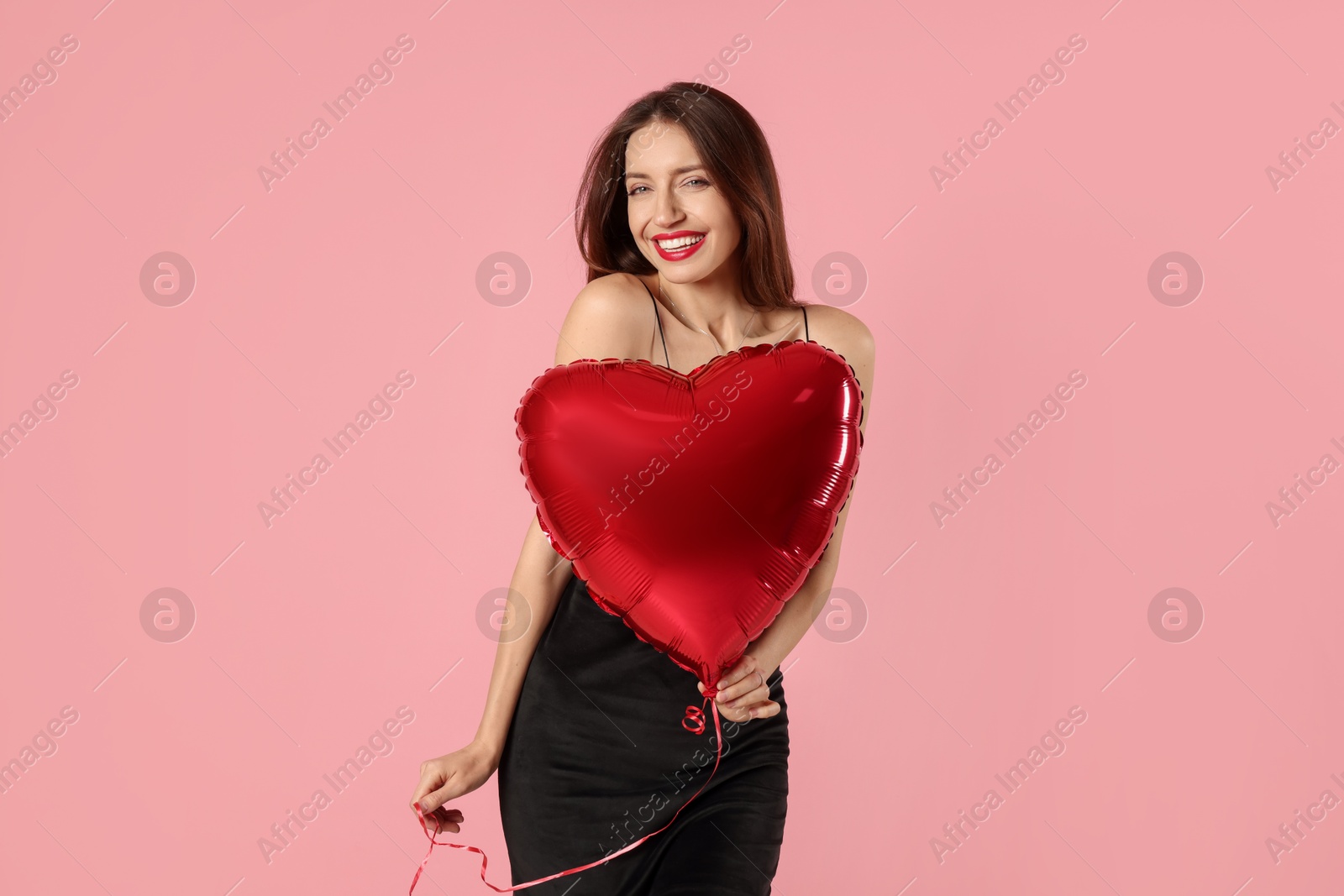 Photo of Happy Valentine's Day. Beautiful woman with heart shaped balloon on pink background