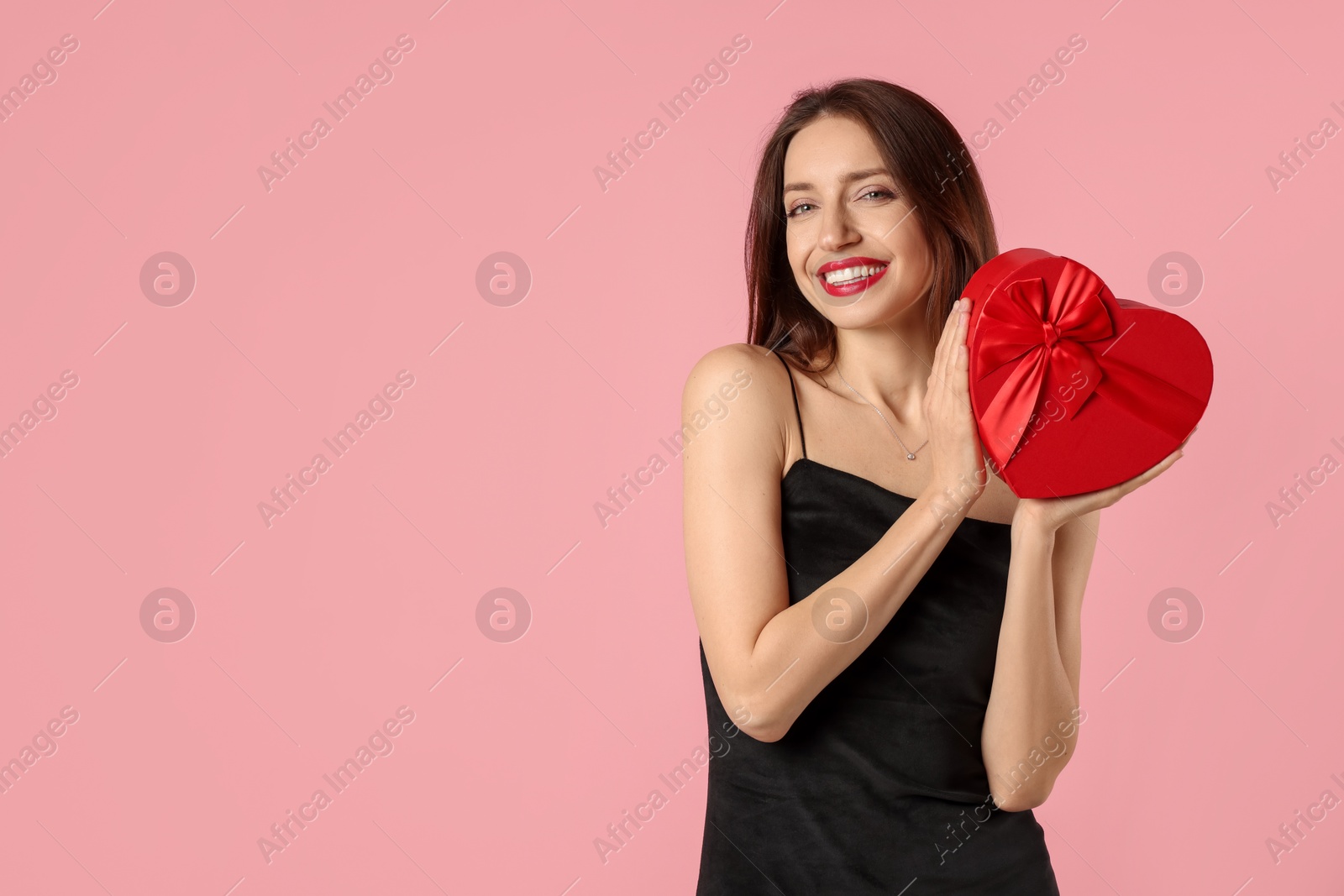 Photo of Happy Valentine's Day. Beautiful woman with heart shaped gift box on pink background. Space for text