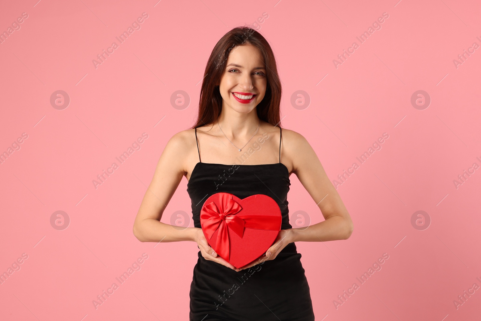 Photo of Happy Valentine's Day. Beautiful woman with heart shaped gift box on pink background