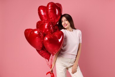 Photo of Happy Valentine's Day. Beautiful woman with heart shaped balloons on pink background