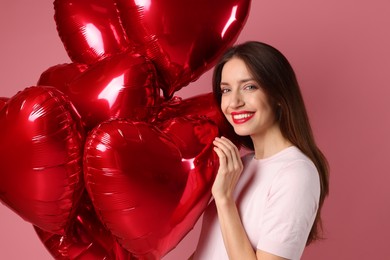 Photo of Happy Valentine's Day. Beautiful woman with heart shaped balloons on pink background