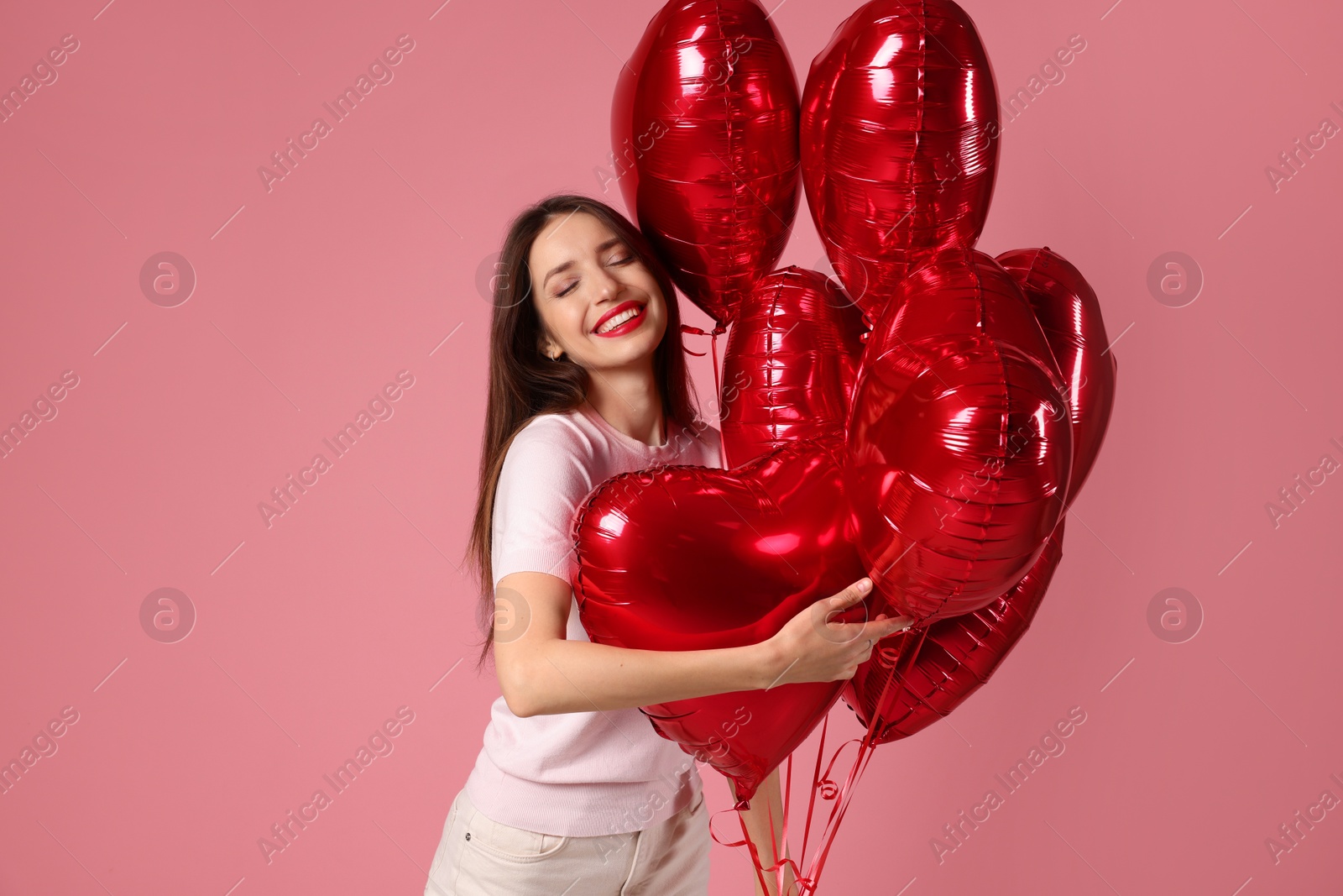 Photo of Happy Valentine's Day. Beautiful woman with heart shaped balloons on pink background