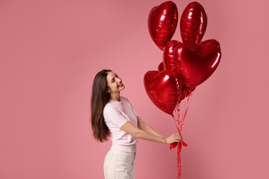 Photo of Happy Valentine's Day. Beautiful woman with heart shaped balloons on pink background