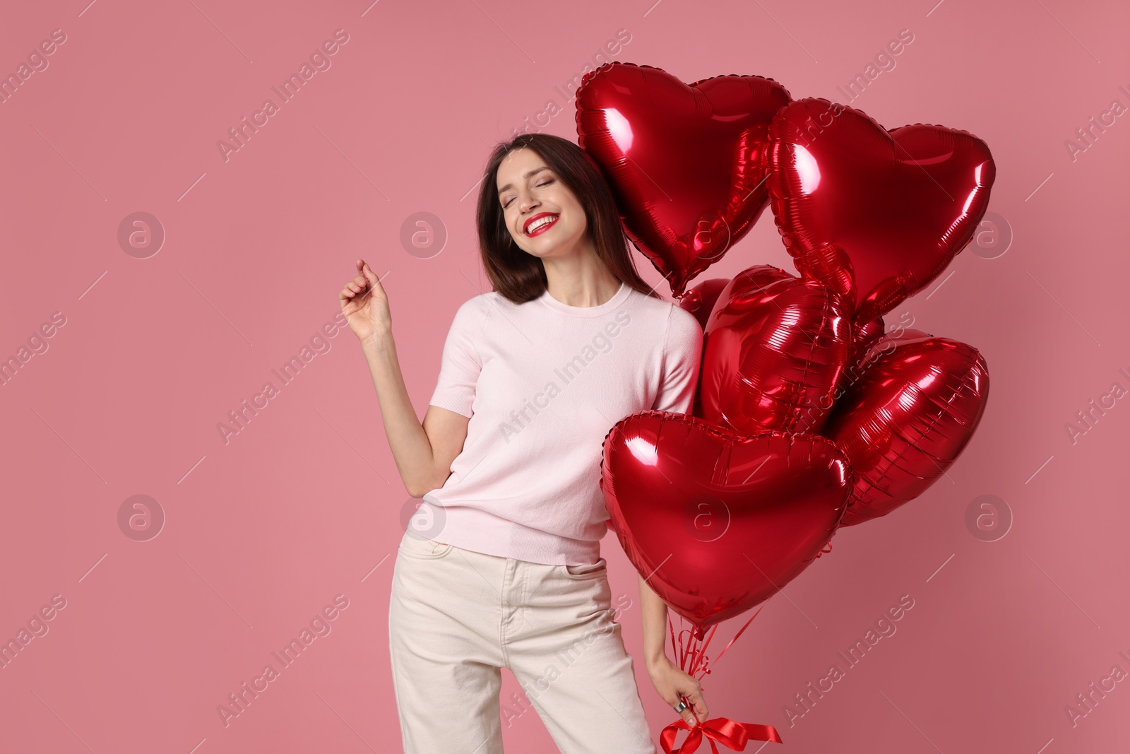 Photo of Happy Valentine's Day. Beautiful woman with heart shaped balloons on pink background