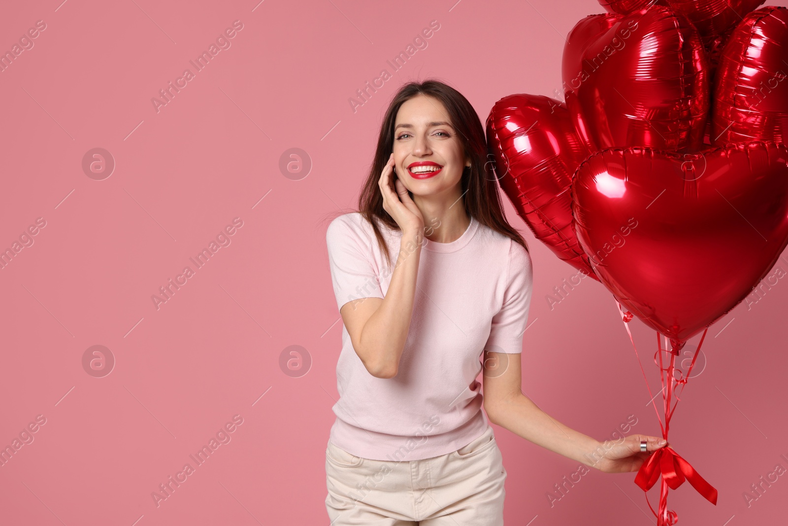 Photo of Happy Valentine's Day. Beautiful woman with heart shaped balloons on pink background. Space for text