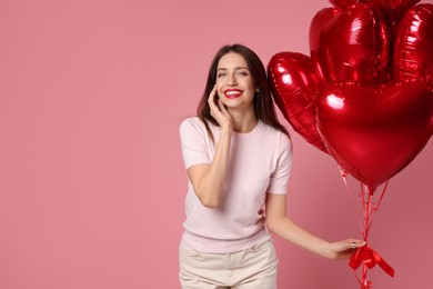 Photo of Happy Valentine's Day. Beautiful woman with heart shaped balloons on pink background. Space for text