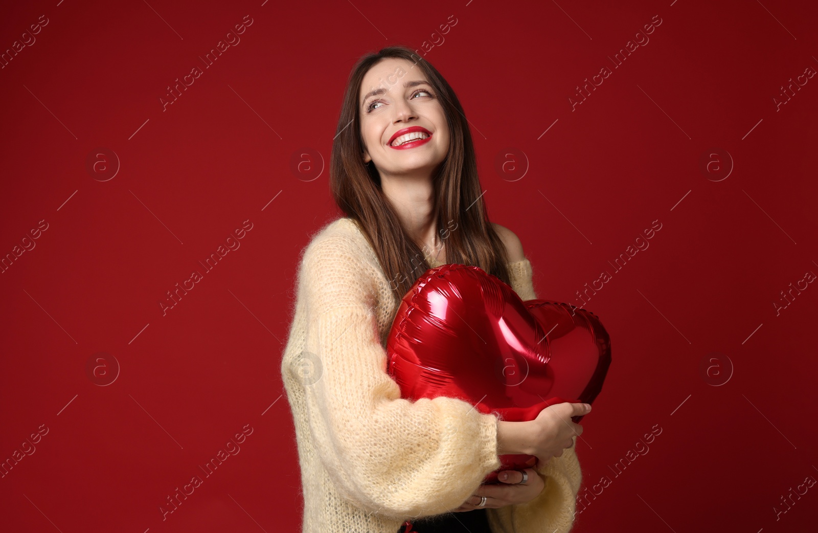 Photo of Happy Valentine's Day. Beautiful woman with heart shaped balloon on red background