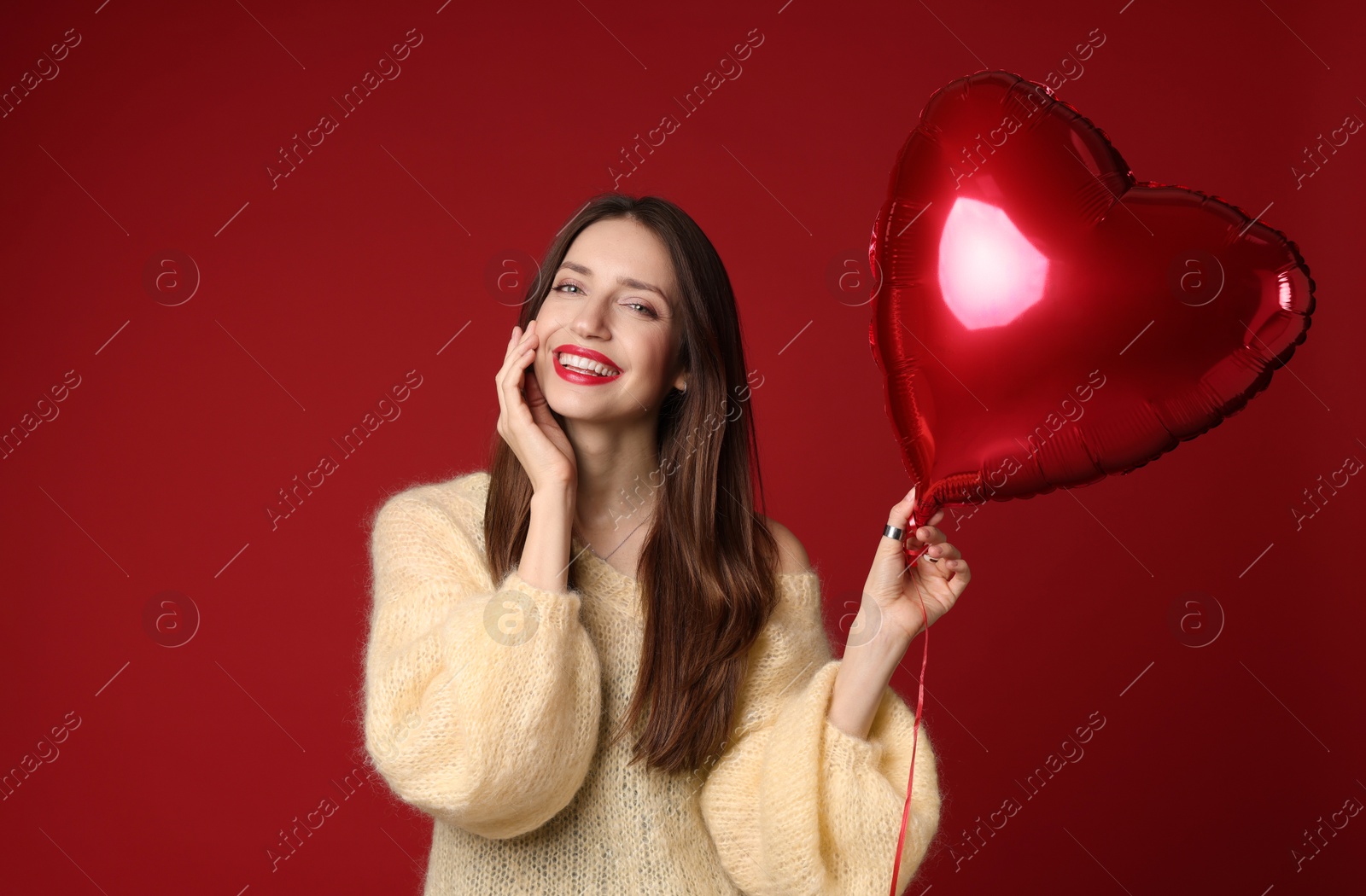 Photo of Happy Valentine's Day. Beautiful woman with heart shaped balloon on red background