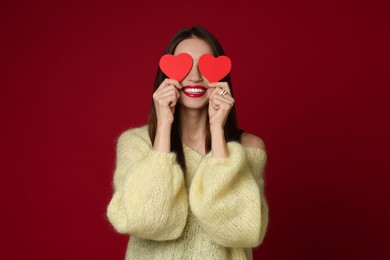 Photo of Happy Valentine's Day. Woman covering her face with paper hearts on red background