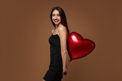 Photo of Happy Valentine's Day. Beautiful woman with heart shaped balloon on brown background