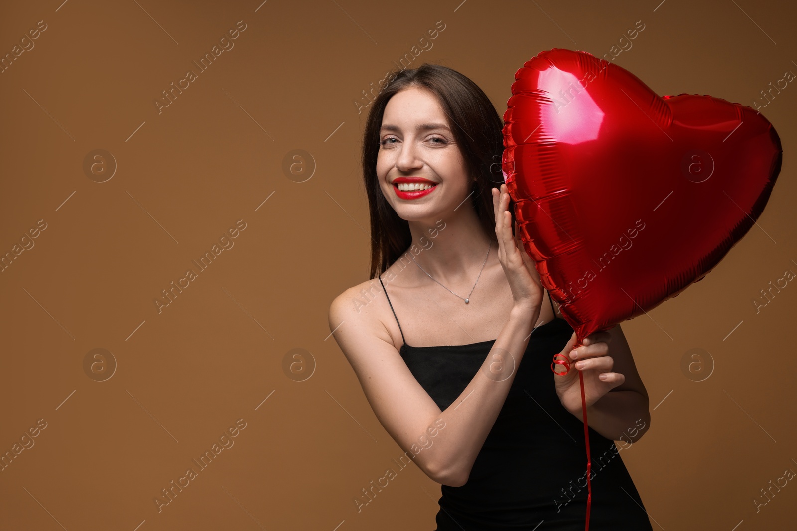 Photo of Happy Valentine's Day. Beautiful woman with heart shaped balloon on brown background. Space for text