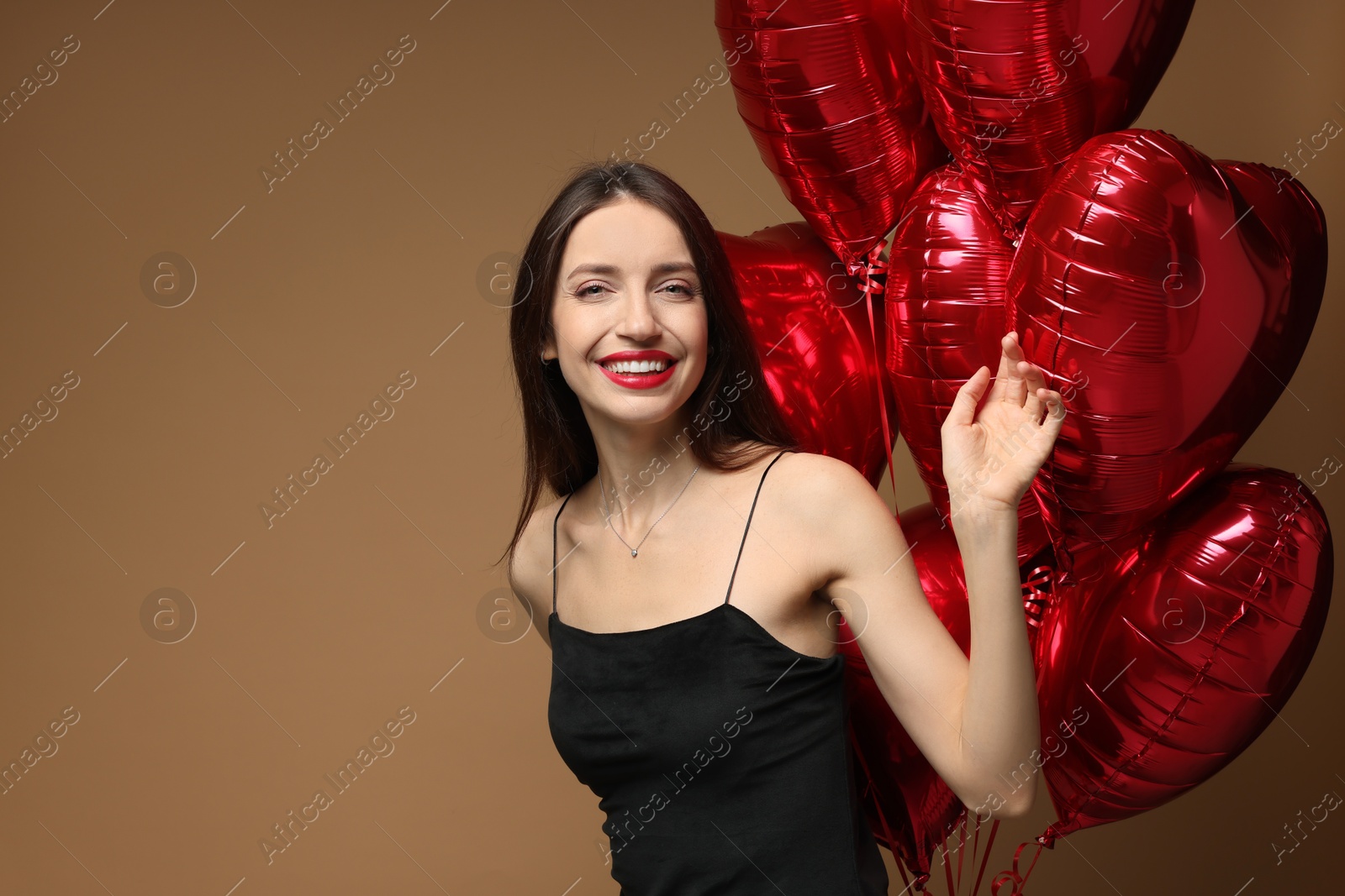 Photo of Happy Valentine's Day. Beautiful woman with heart shaped balloons on brown background. Space for text