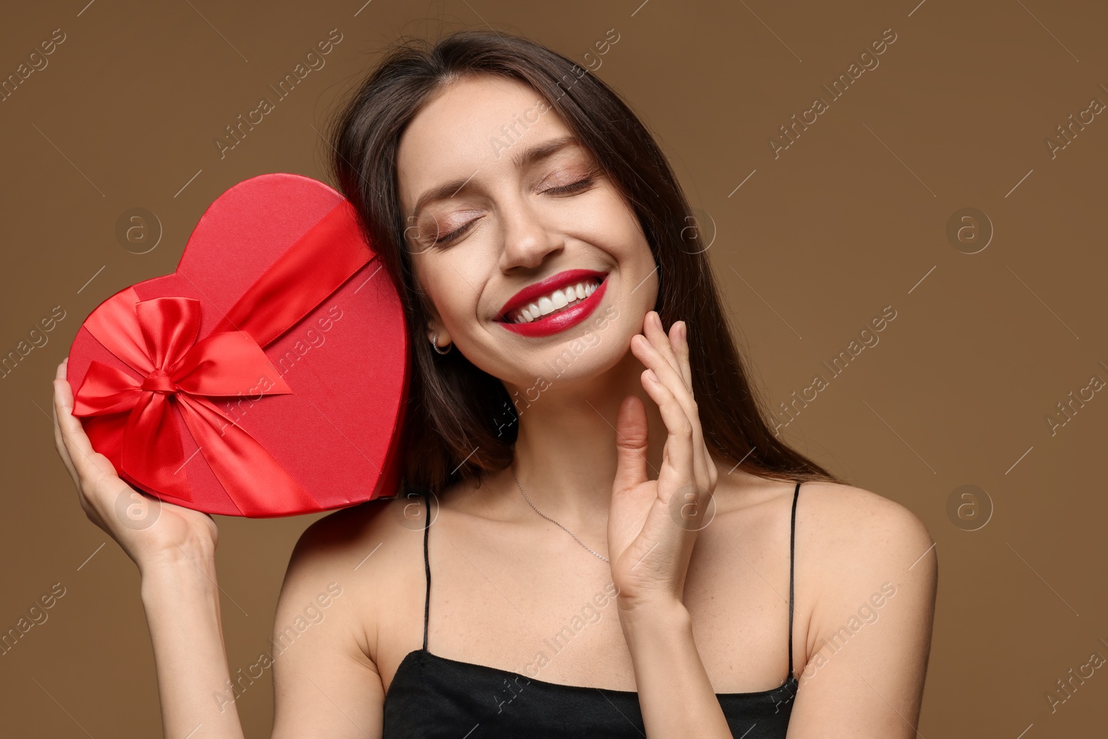 Photo of Happy Valentine's Day. Beautiful woman with heart shaped gift box on brown background