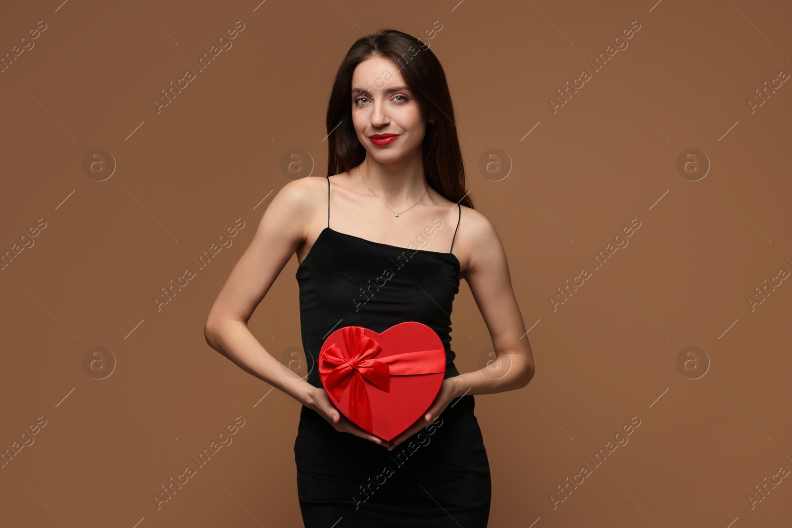 Photo of Happy Valentine's Day. Beautiful woman with heart shaped gift box on brown background