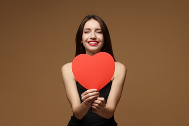 Photo of Happy Valentine's Day. Beautiful woman with paper heart on brown background