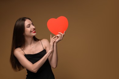 Photo of Happy Valentine's Day. Beautiful woman with paper heart on brown background. Space for text