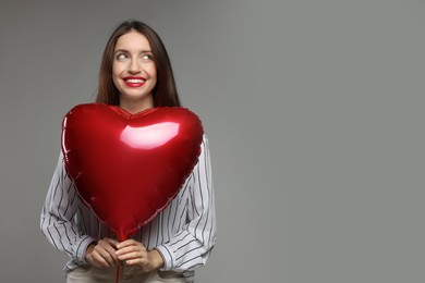 Photo of Happy Valentine's Day. Beautiful woman with heart shaped balloon on grey background. Space for text