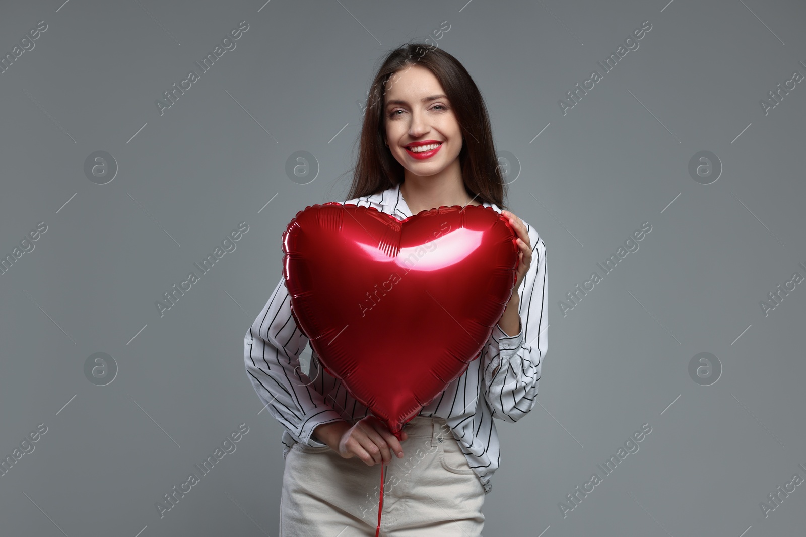 Photo of Happy Valentine's Day. Beautiful woman with heart shaped balloon on grey background