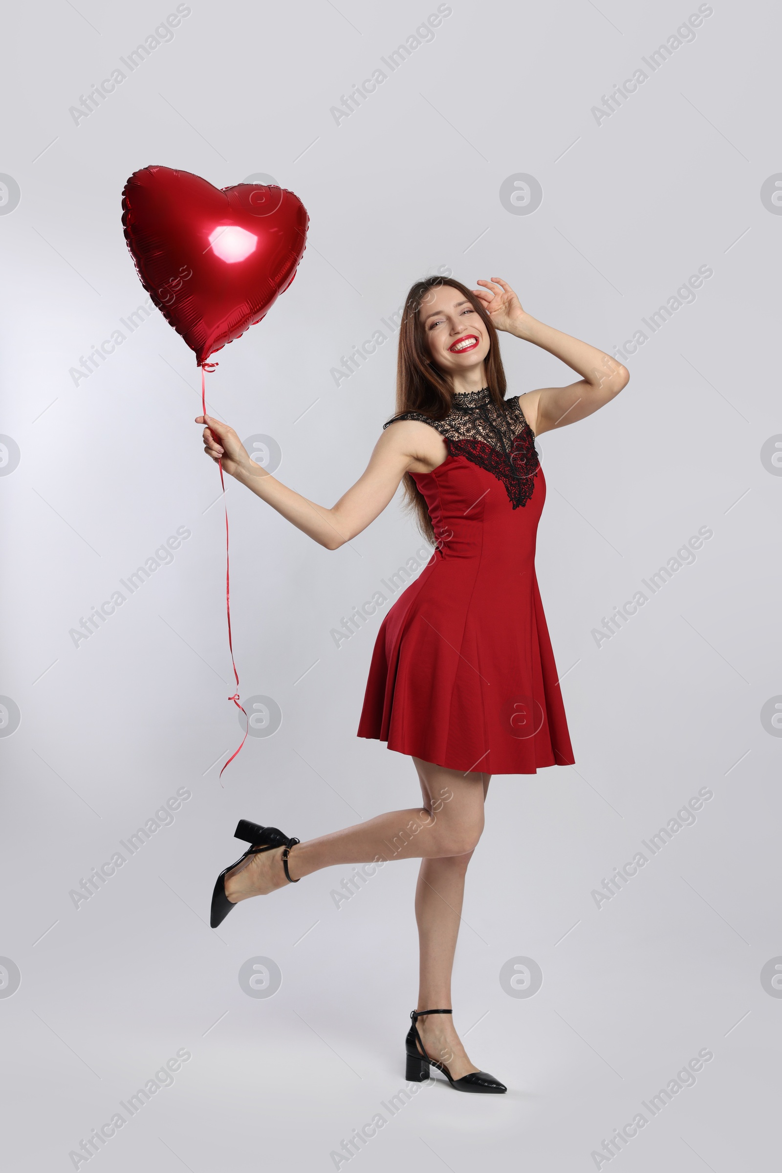 Photo of Happy Valentine's Day. Beautiful woman with heart shaped balloon on white background