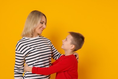 Photo of Mother and son hugging on orange background