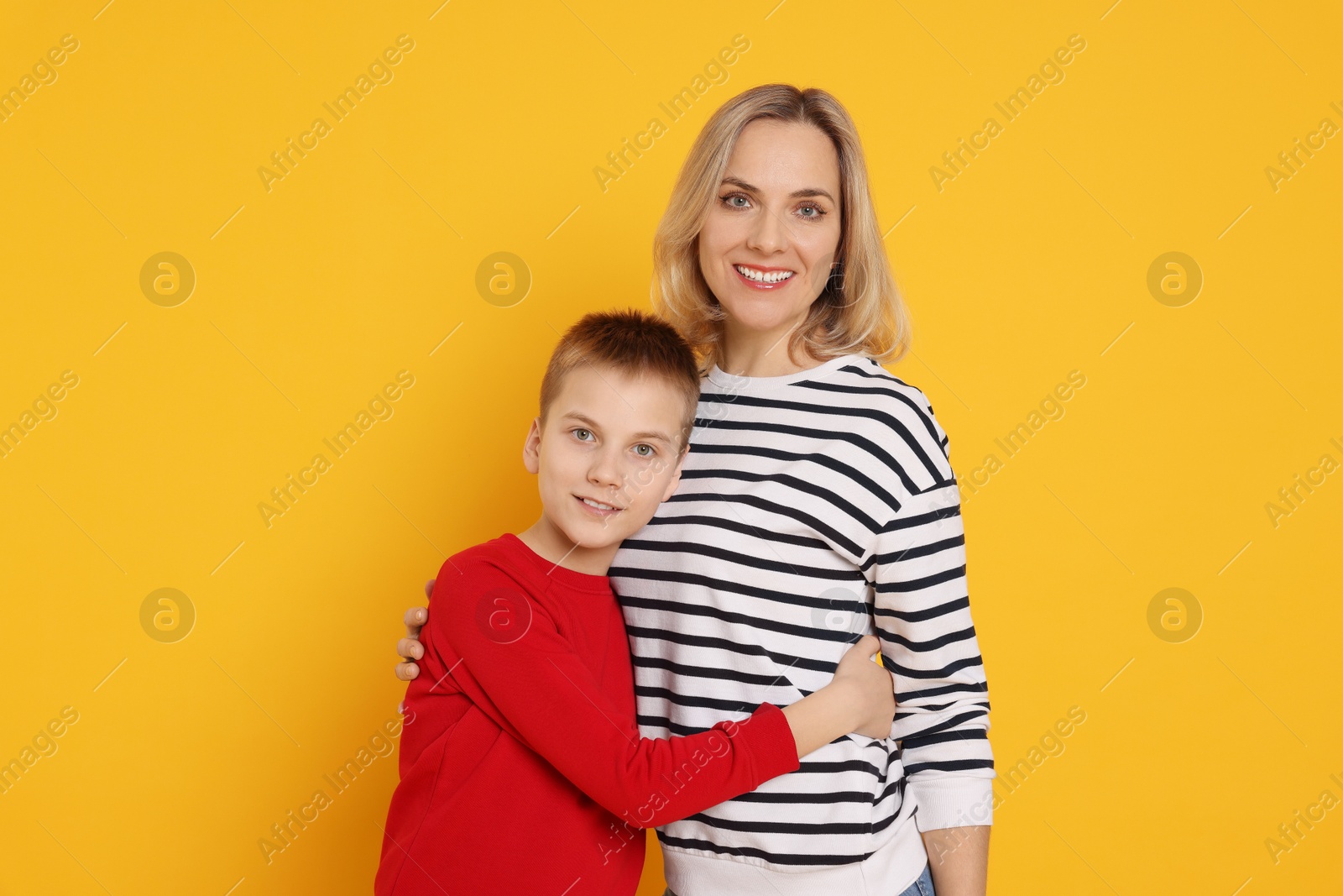 Photo of Mother and son hugging on orange background