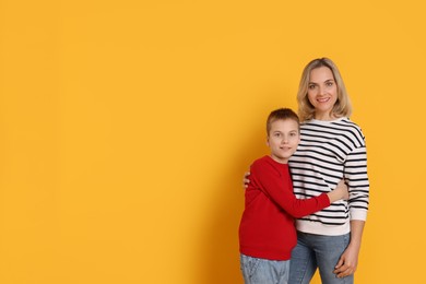 Photo of Happy mother and son on orange background. Space for text