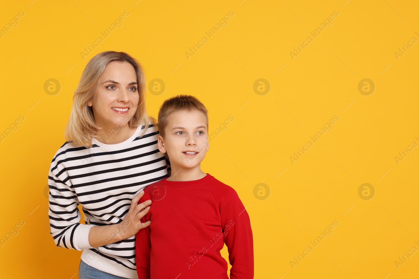 Photo of Happy mother and son on orange background. Space for text