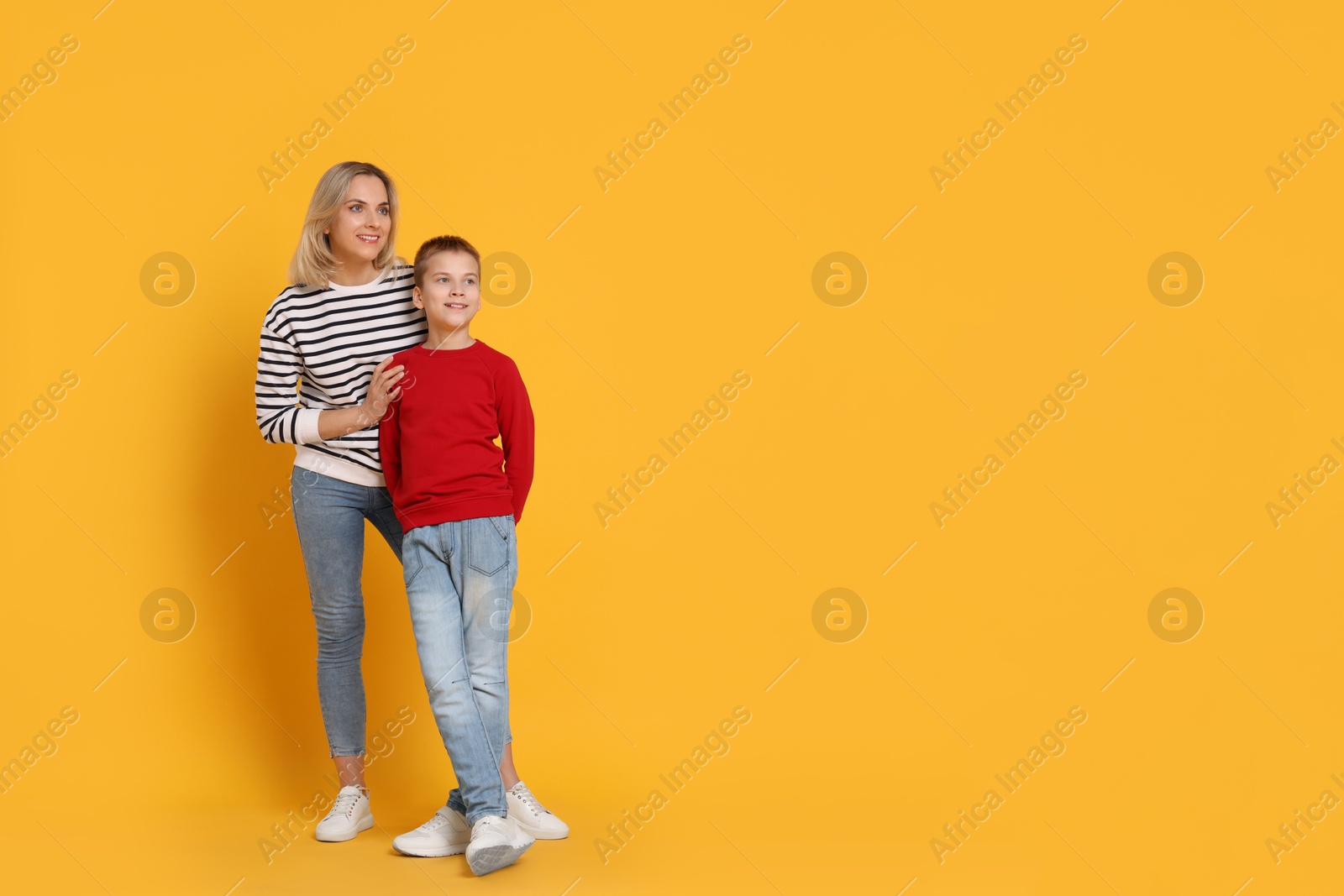 Photo of Happy mother and son on orange background. Space for text