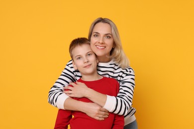 Photo of Mother and son hugging on orange background