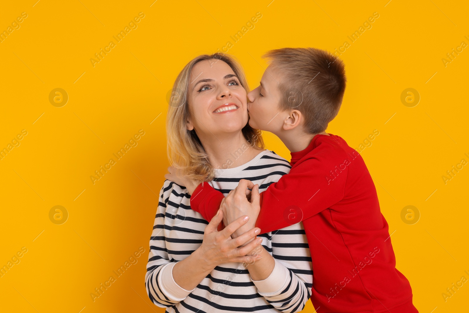 Photo of Son kissing his mom on orange background