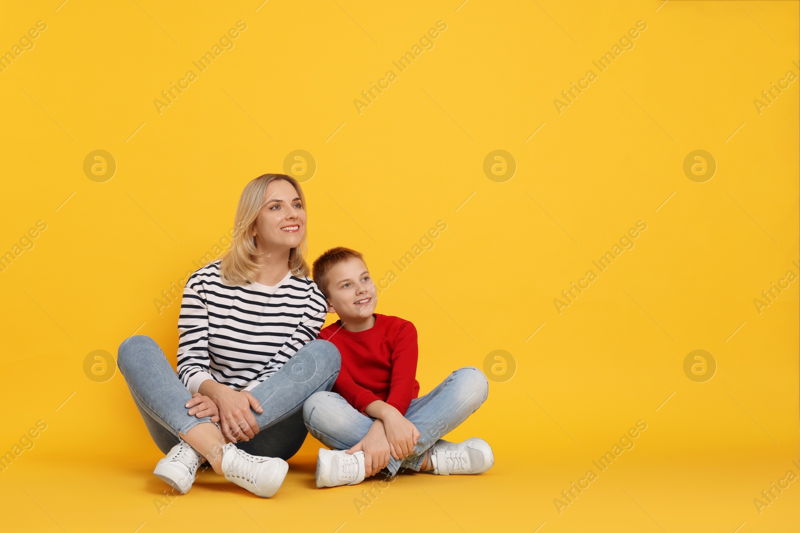 Photo of Happy mother and son on orange background. Space for text