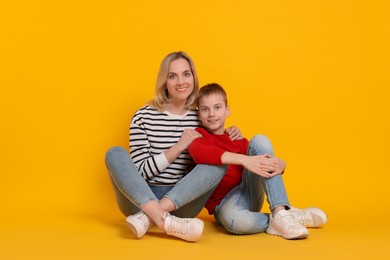 Photo of Happy mother and son on orange background