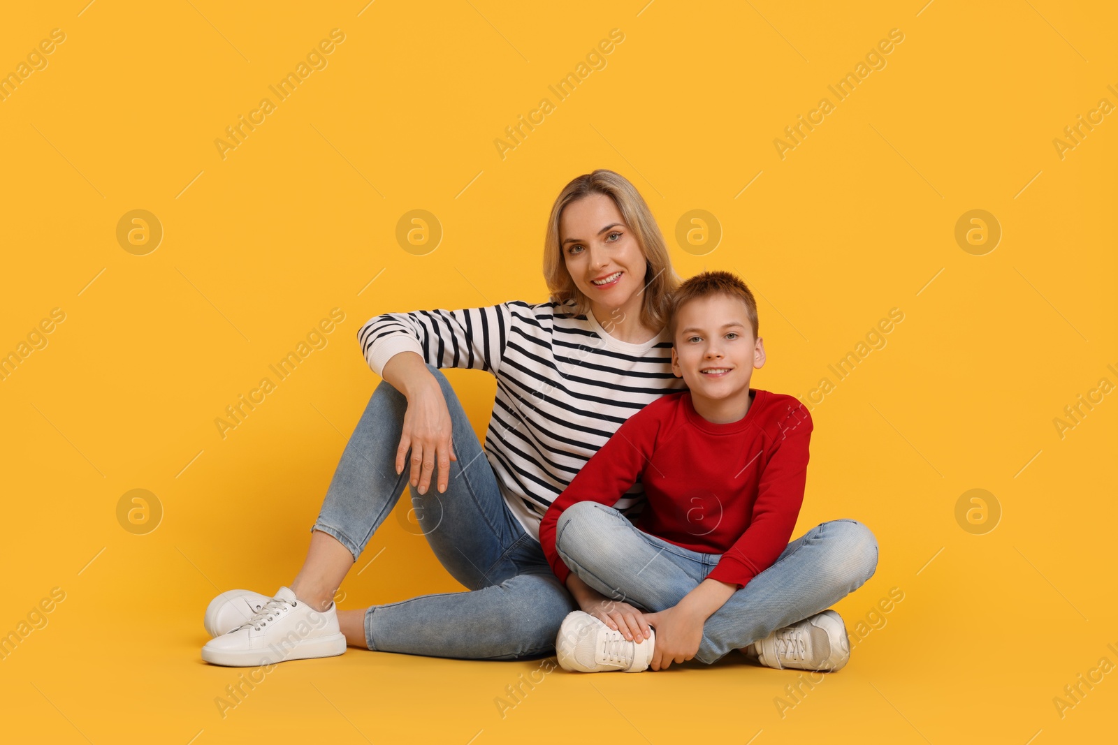 Photo of Happy mother and son on orange background