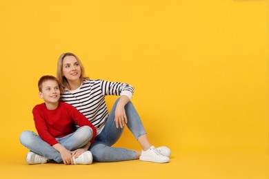 Photo of Happy mother and son on orange background. Space for text